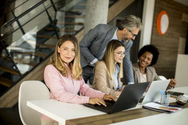 Group of pretty young multiethnic business women working on new project with supervising by the mature boss
